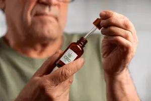 Older man holding CBD oil dropper bottle
